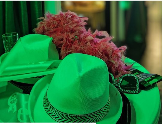 Chapeaux, boa en plumes et lunettes de la malle d'accessoires, sous la lumière verte de la salle